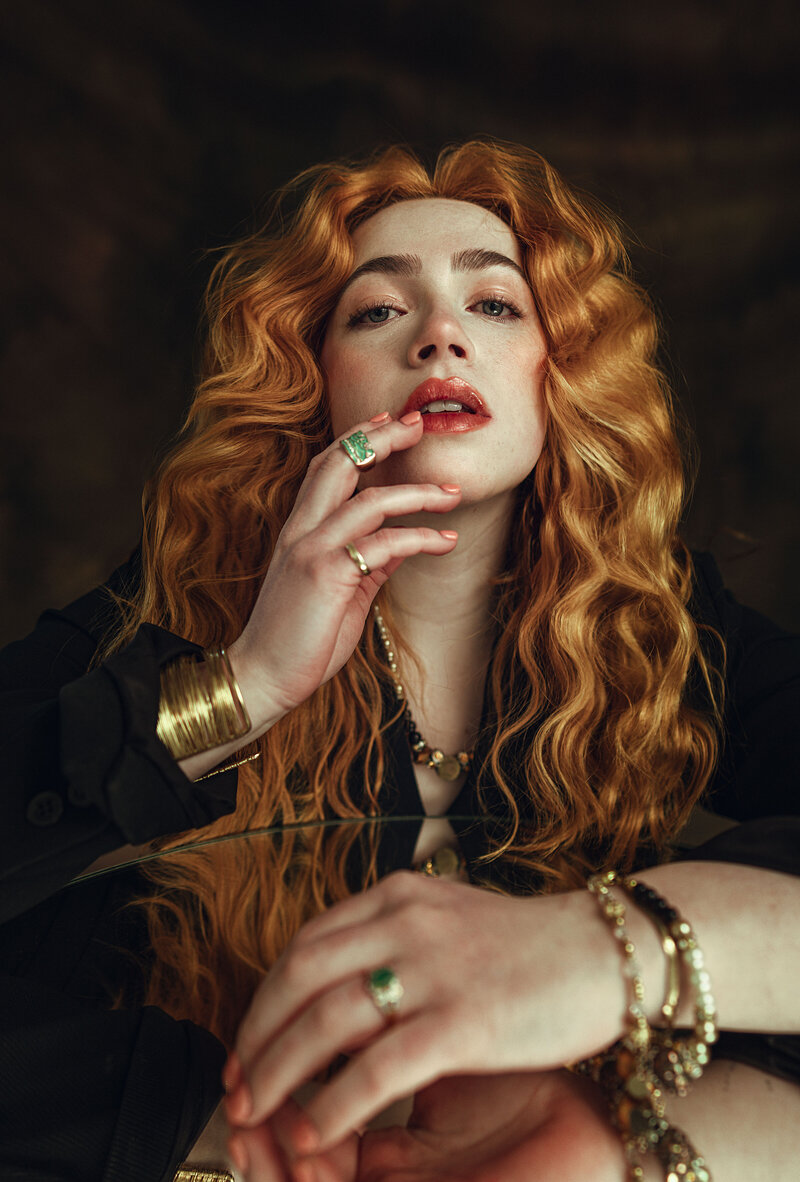 Red headed model posing with hand touching her face. 