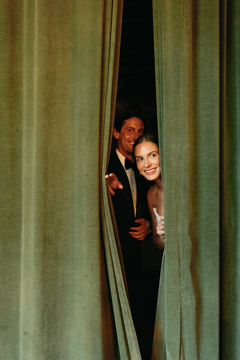 A candid image of a couple on their wedding day at the Bowery Hotel in front of a green velvet curtian