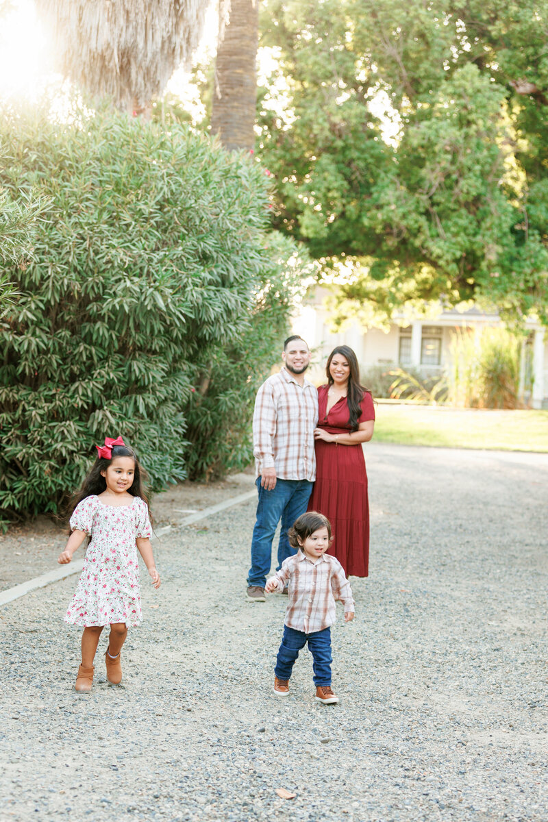 Kids being playful while parents look on in a park like setting during a photo shoot with Fresno, CA family photographer 