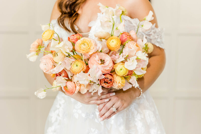 Bride holding pink, orange, yellow and white florals, bridal bouquet Fete Inc, Fete Wales.