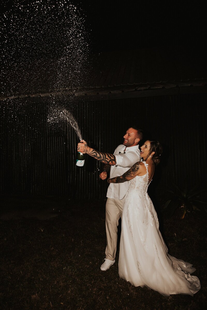 Couple popping champagne at night after their St. Augustine elopement