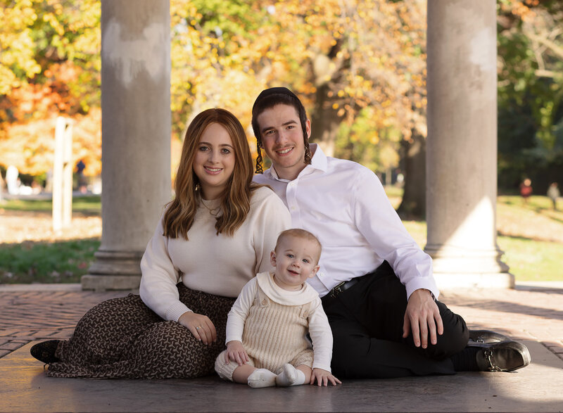 Family sits under a brooklyn portico for a family photoshoot. Captured by top Brooklyn, NY newborn photographer Chaya Bornstein Photography.