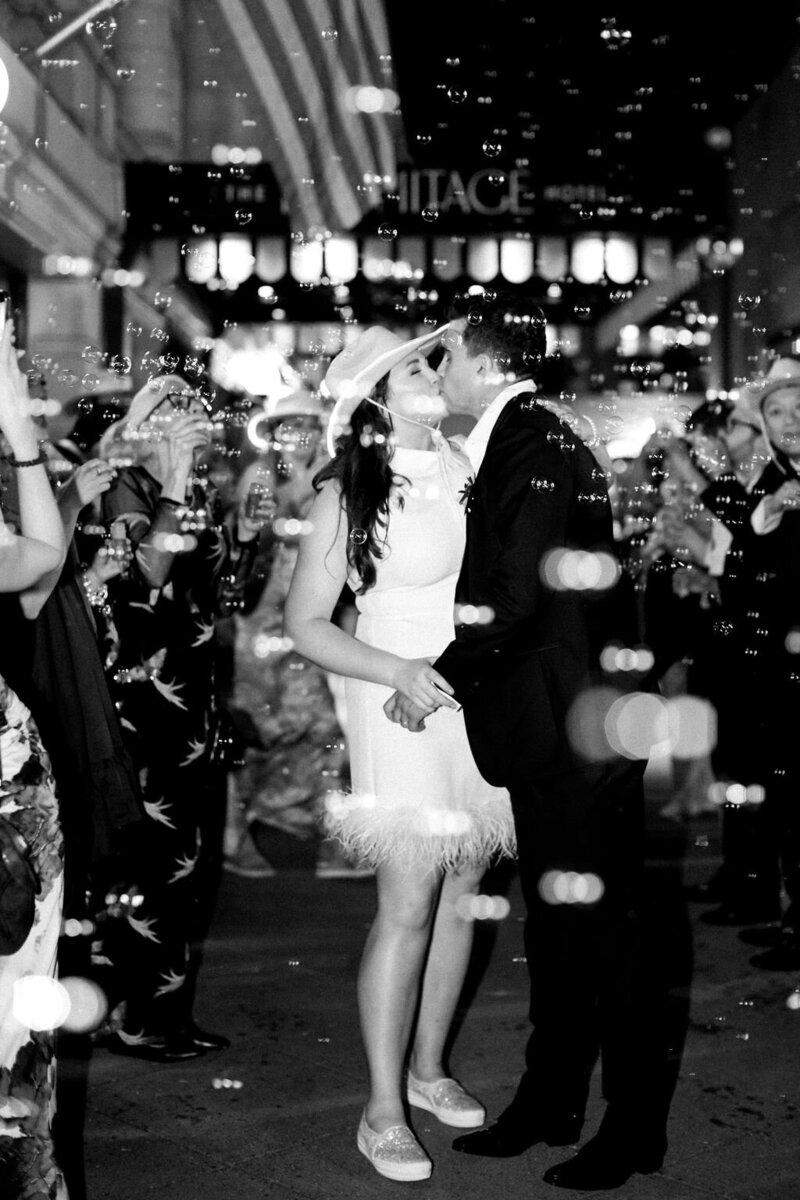 Bride and groom kiss with bubbles blown by guests outside the Hermitage Hotel in Nashville