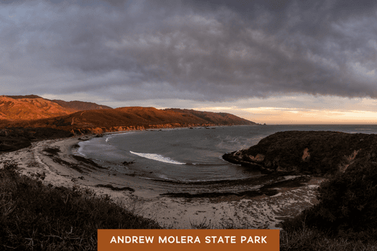 A rugged coastline at Andrew Molera State Park glows under golden light, with waves curving into the shore.