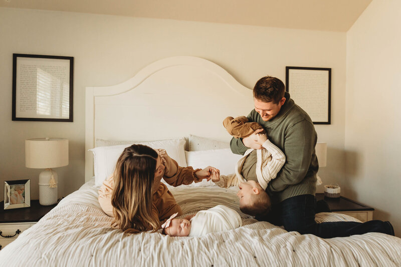 Family playing on a white bed