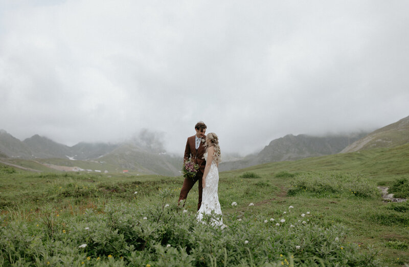 A couple embracing one another while surrounded by mountains.