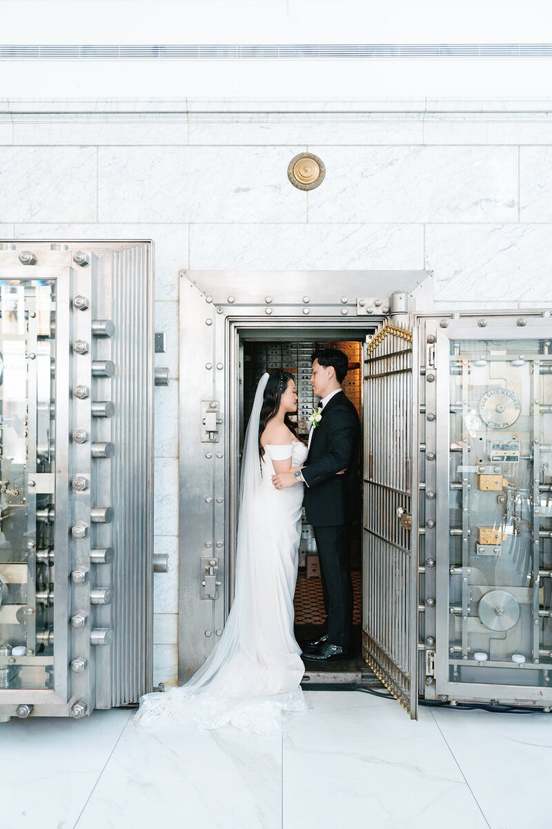 Bride and groom posing in the doorway of an old bank vault