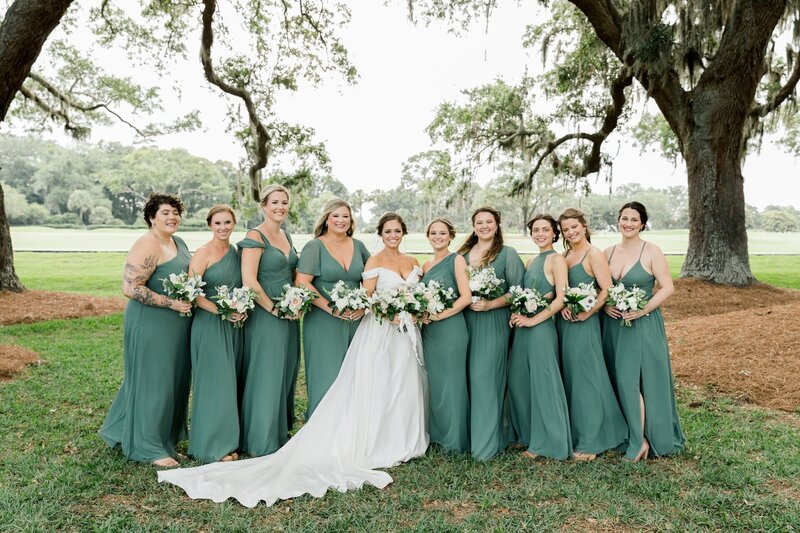 a bride standing with her bridesmaids who are wearing green dresses