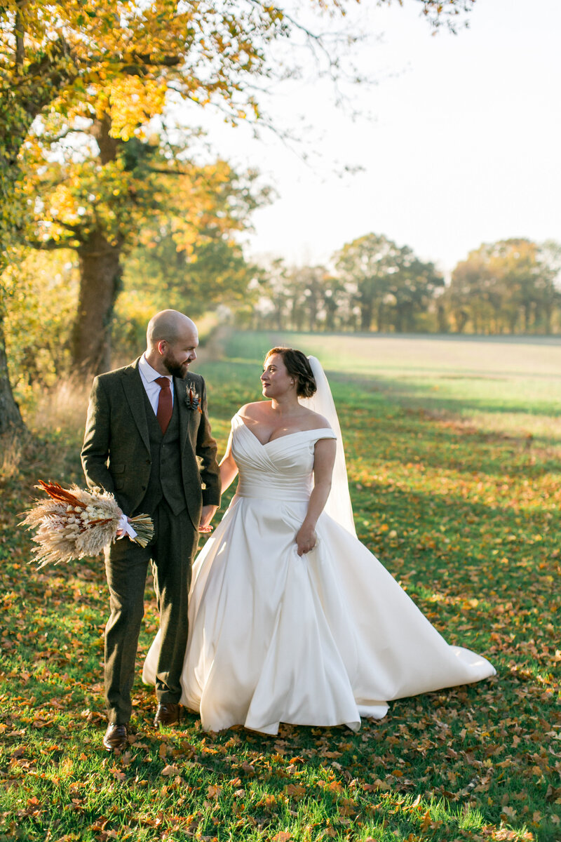 Hertfordshire bride and groom walking in the fields at their Autumn Wedding
