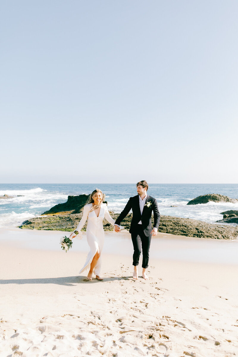 candid photo of bride and groom frollicking on the beach