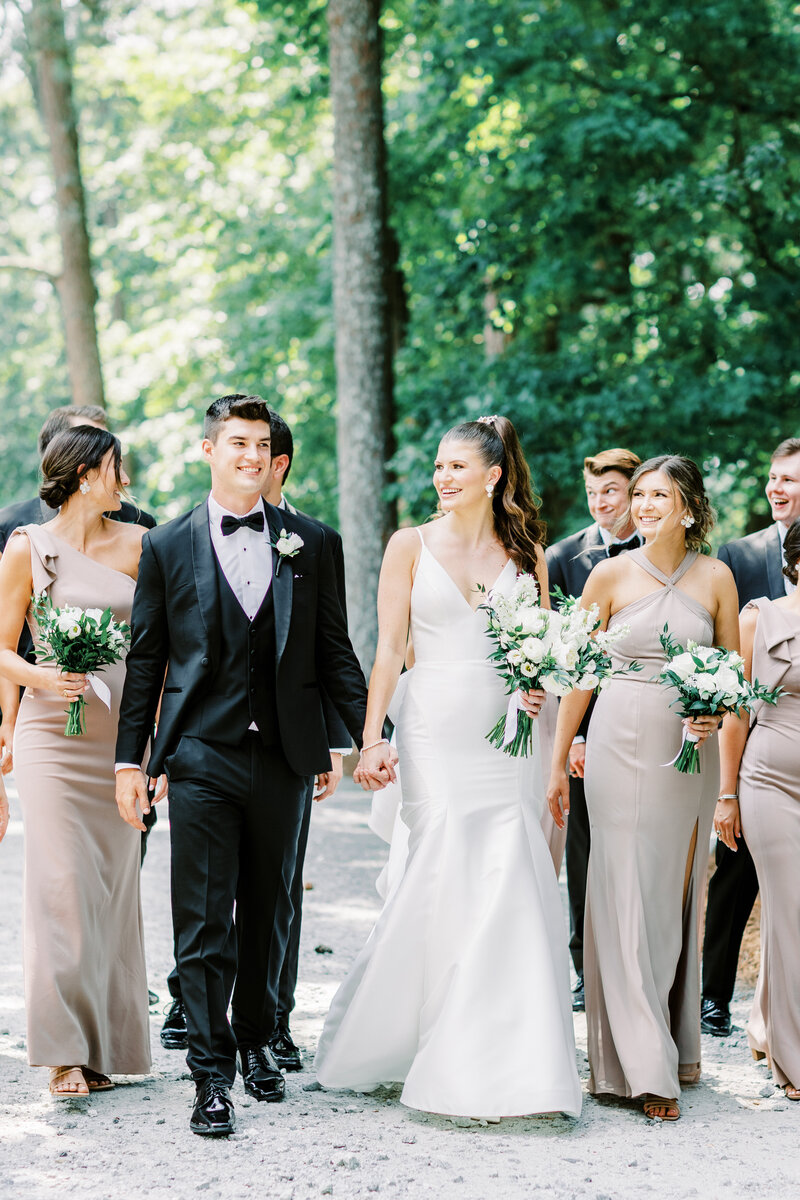 Bride and groom holding hands and walking with bridal party outside