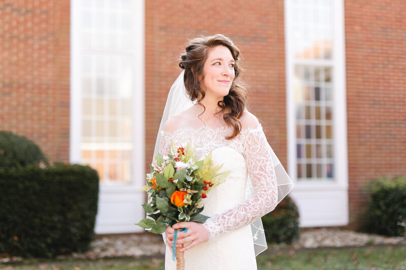 bride in lace dress holding her flowers and looking over her shoulder Miranda Renee Photography