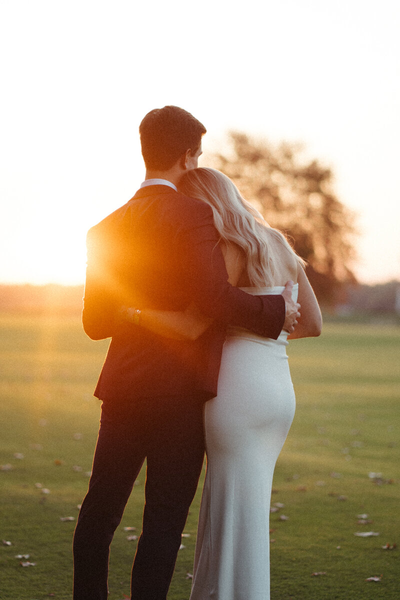 Couple embracing after elopement celebration looking into the sunset