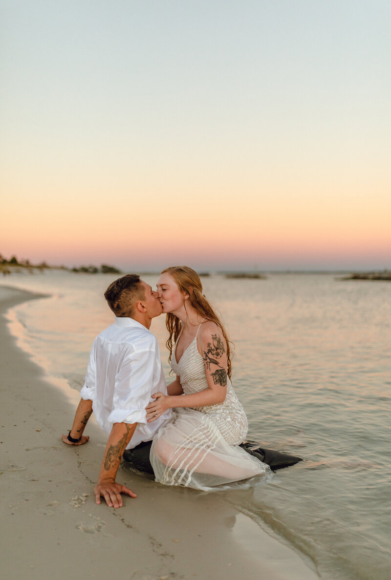 young newlyweds kiss intimately on shore of St. Andrews State park in PCB .  By Panama City Beach photographer Brittney Stanley