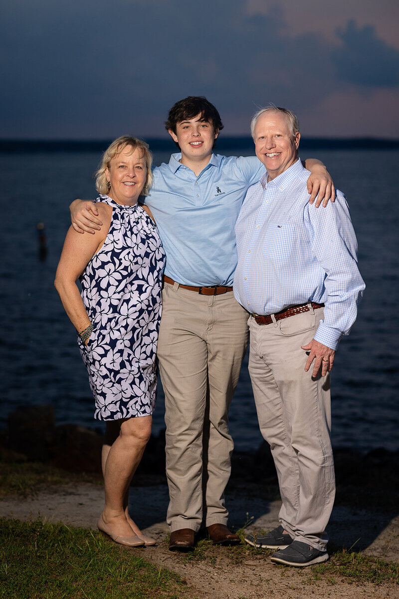 a high school senior taking a photo with his parents