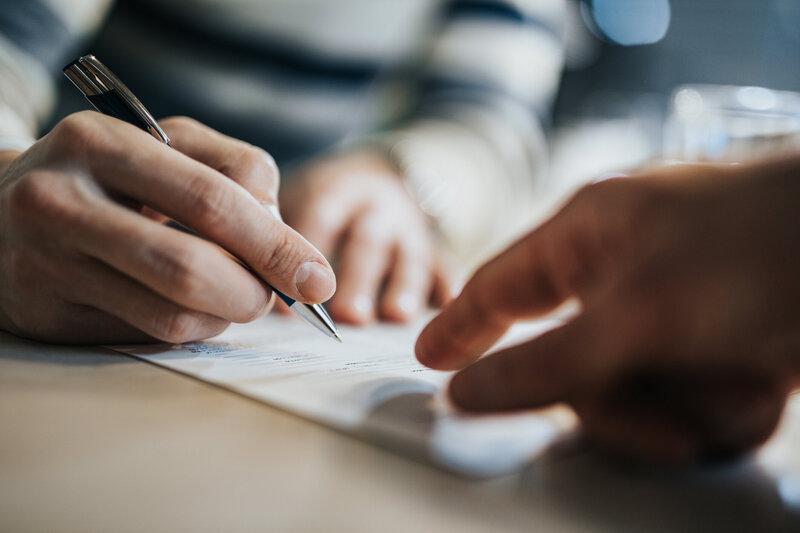 Close up of hands signing a document