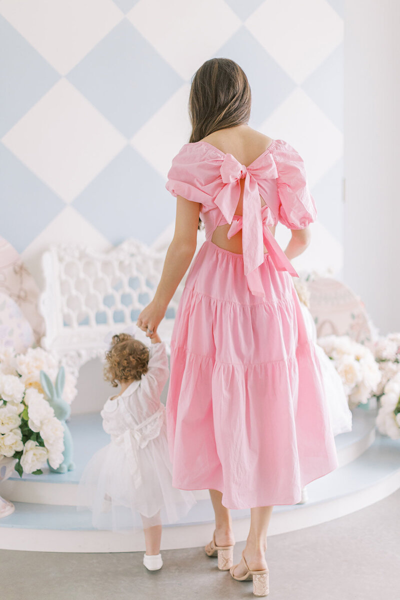 Woman in a long pink dress holding the hand of a little girl