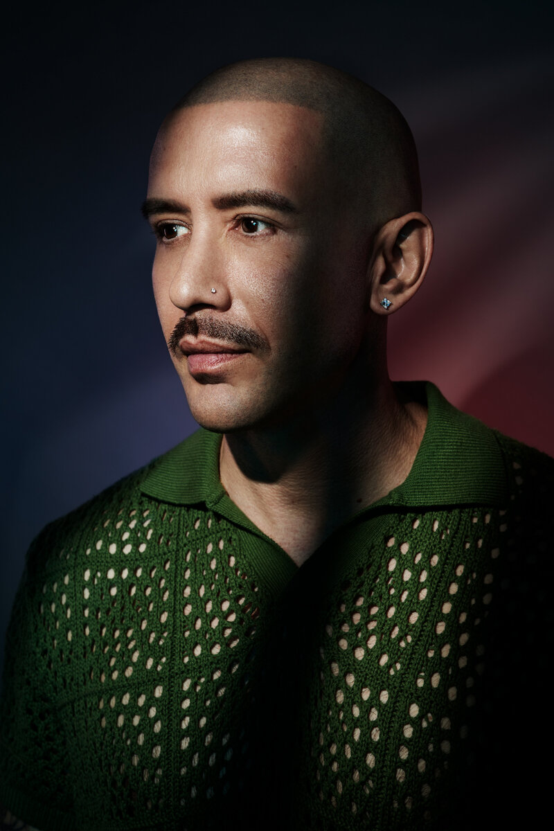 Stylized studio portrait of Ray Contreras in a green textured shirt, with dramatic lighting and a dark background, captured by Ylva Erevall.