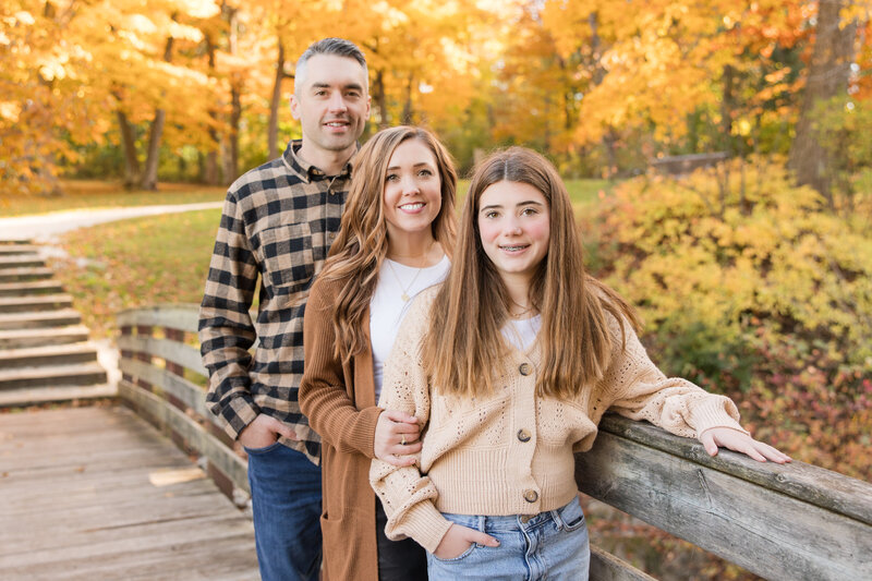 Family standing together on a bridge and smiling at the camera