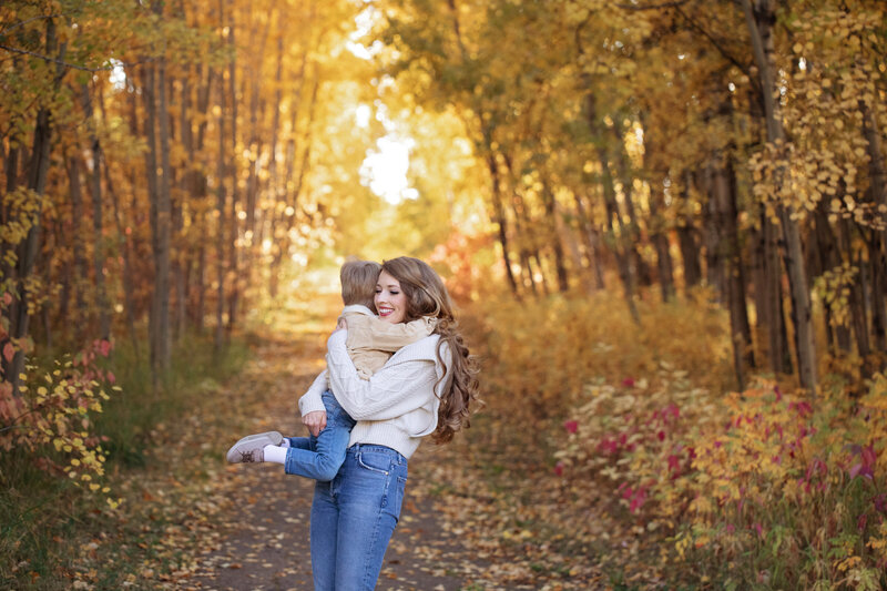 Mom holding son in fall forest