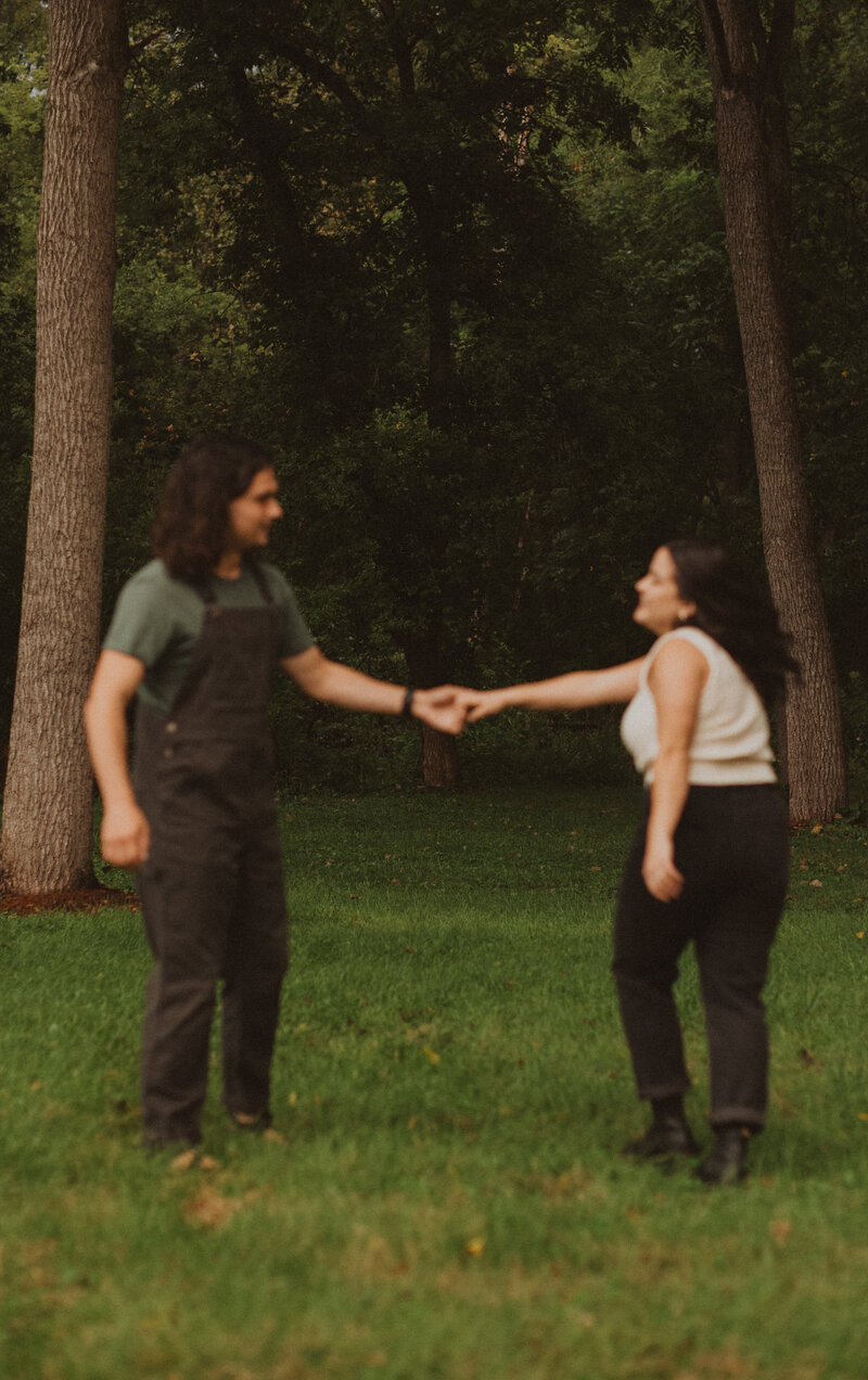 couple holing hands and chasing each other in a grass field