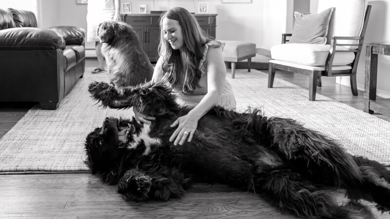 A black-and-white image of a woman scratching her dog's belly, capturing a joyful moment at home near Phoenixville.