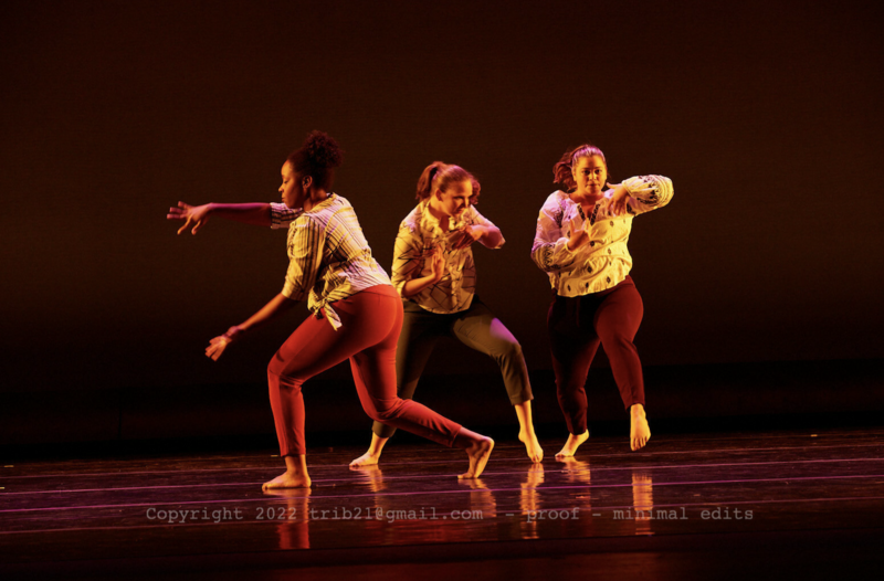 Three woman in modern dance positions on stage at a recital