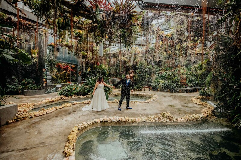 DC Calligrapher and her husband holding hands exploring a whimsical garden destination