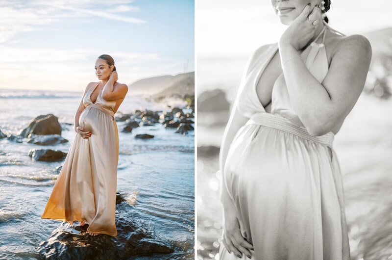 A mom in a gold dress standing on a rock in the surf during her beach maternity session