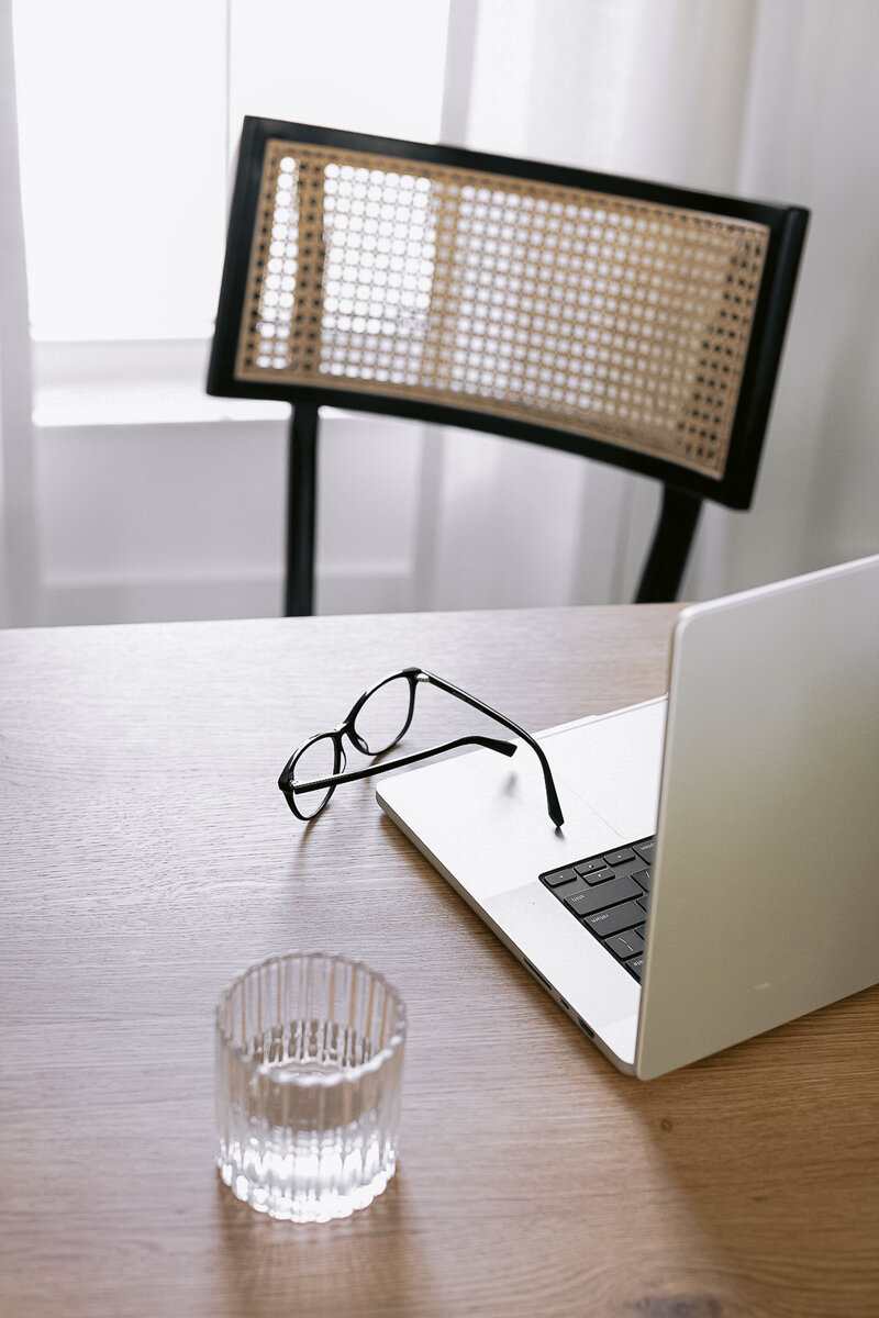 Laptop, glasses, and a cup of water on a table