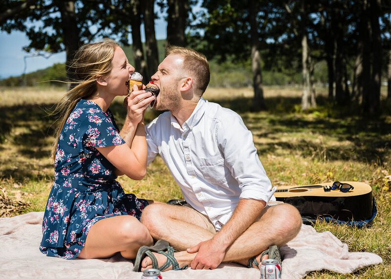 A couple on their elopement day in Shenandoah National Park sit for a picnic and eat cupcakes together.