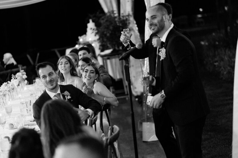 Groom laughs with bride during toasts at Glen Foerd Estate in Philadelphia, PA