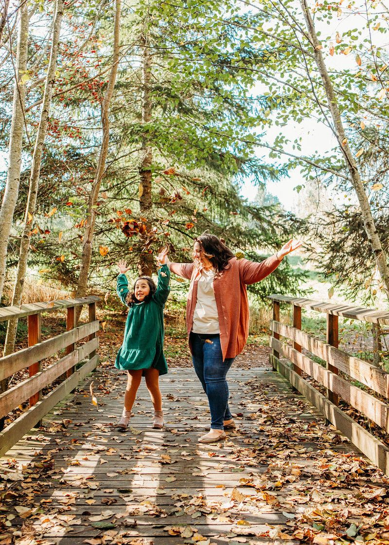 university place newborn photographer keli vaeagi throwing leaves and laughing with her daughter