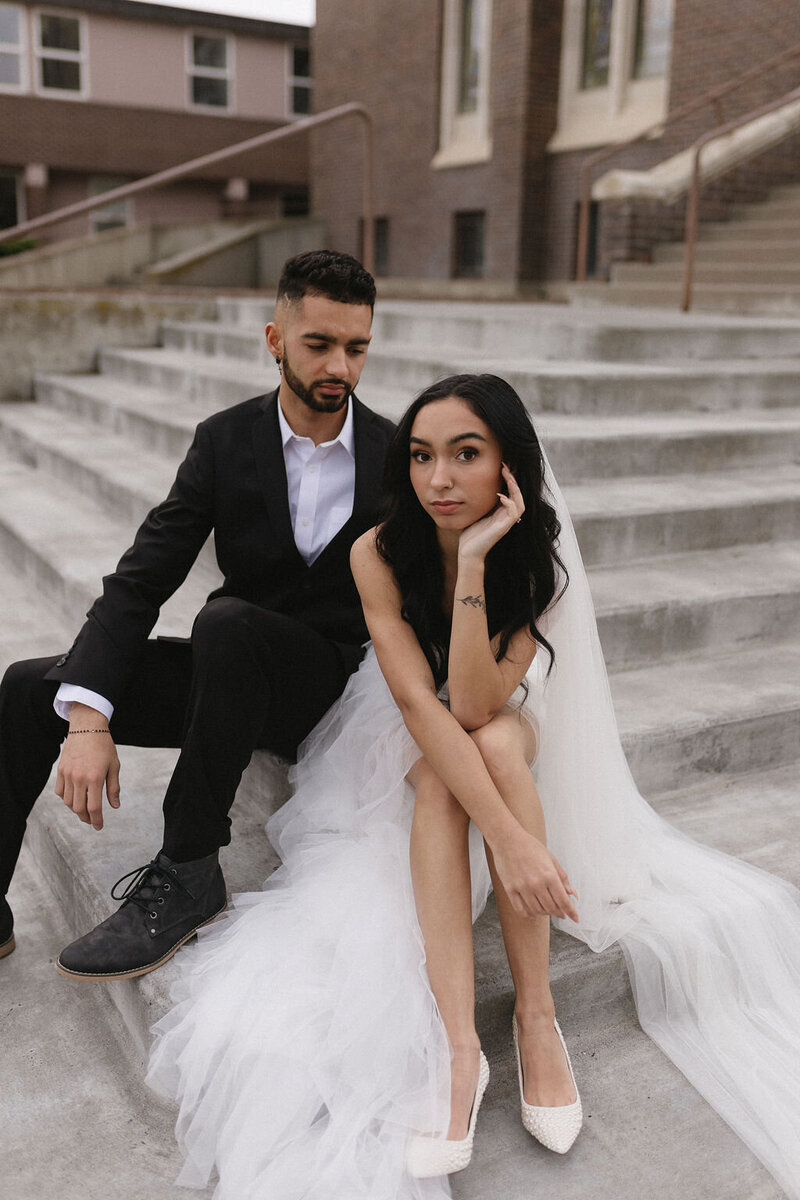 Bride and groom sitting on steps in their wedding attire.