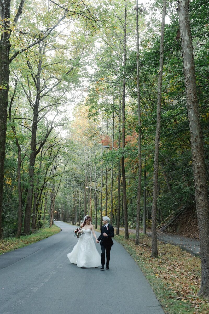 Bride and groom walking hand in hand on forest road