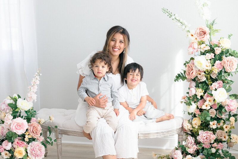 Mom sitting on a bench with her two sons in a bright louisville kentucky family photography studio