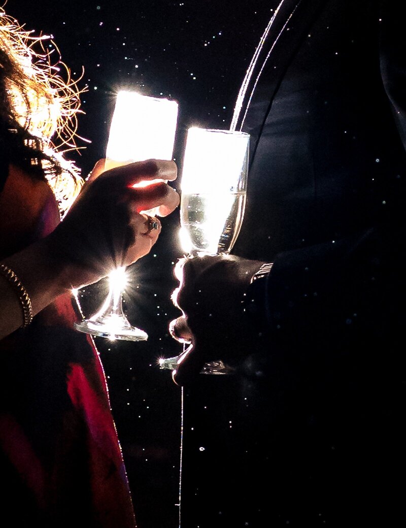 backlit-champagne-glasses-held-by-a-couple