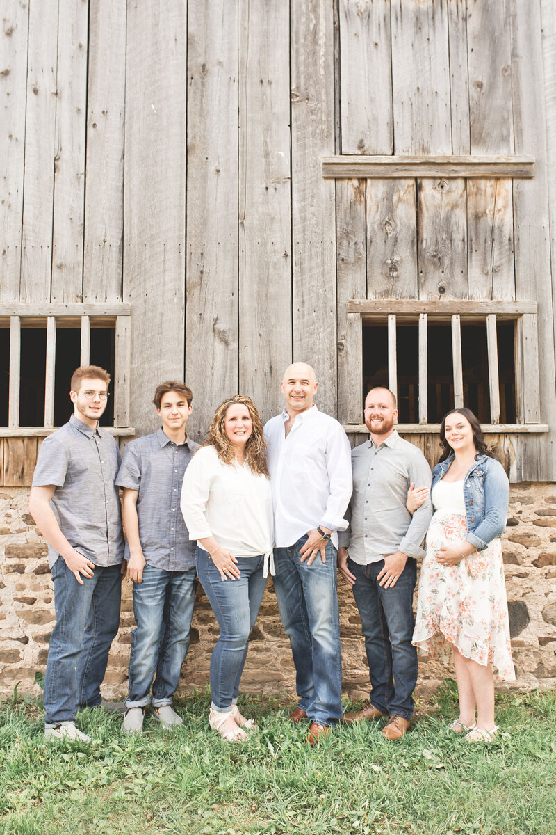 A family portrait full of warmth and unity, taken in front of a wooden barn—rustic and timeless.