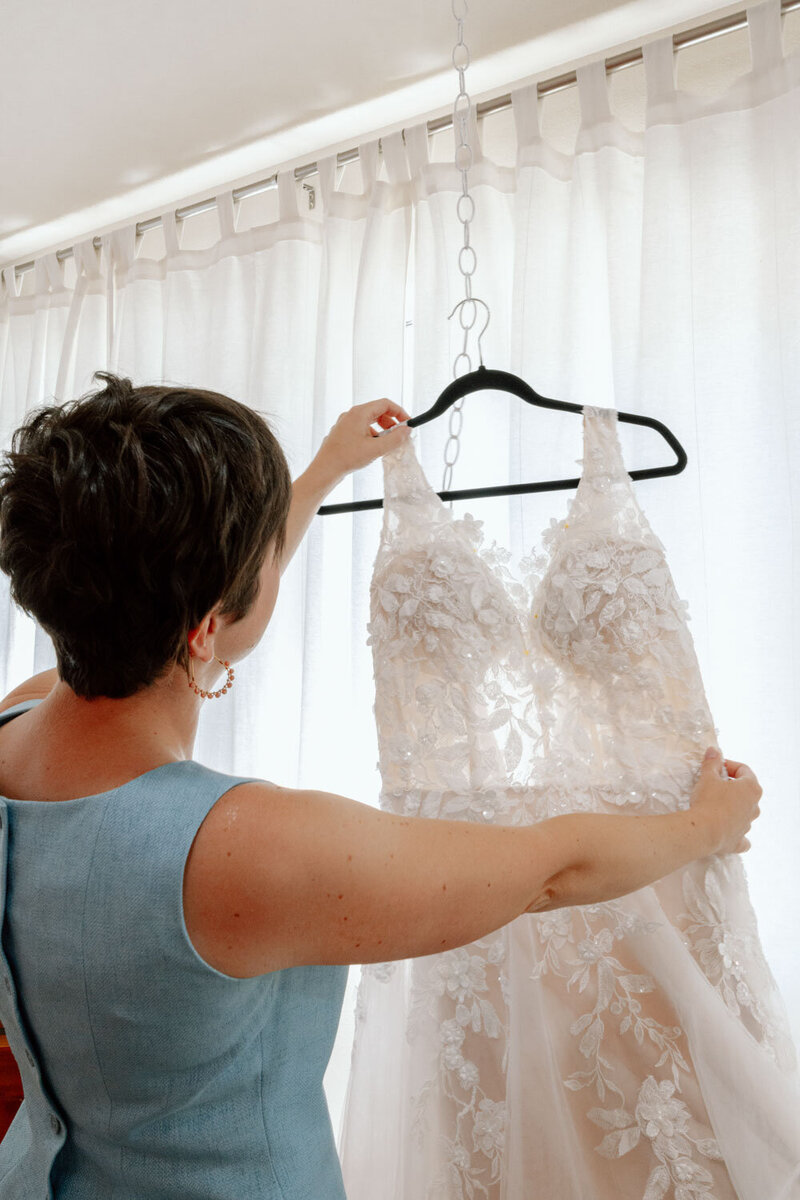 A seamstress carefully holding a lace wedding gown