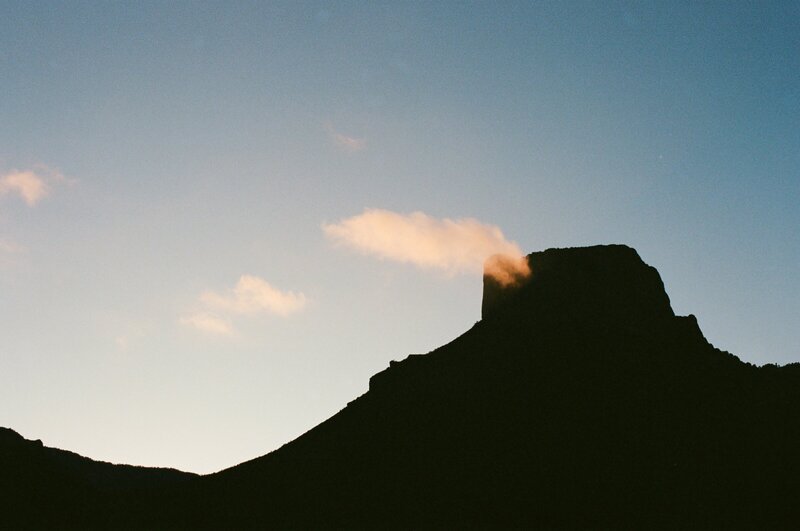 Silhouetted desert peak at golden hour in West Texas with rich shadows and painterly skies, styled in an analog-inspired film aesthetic.

