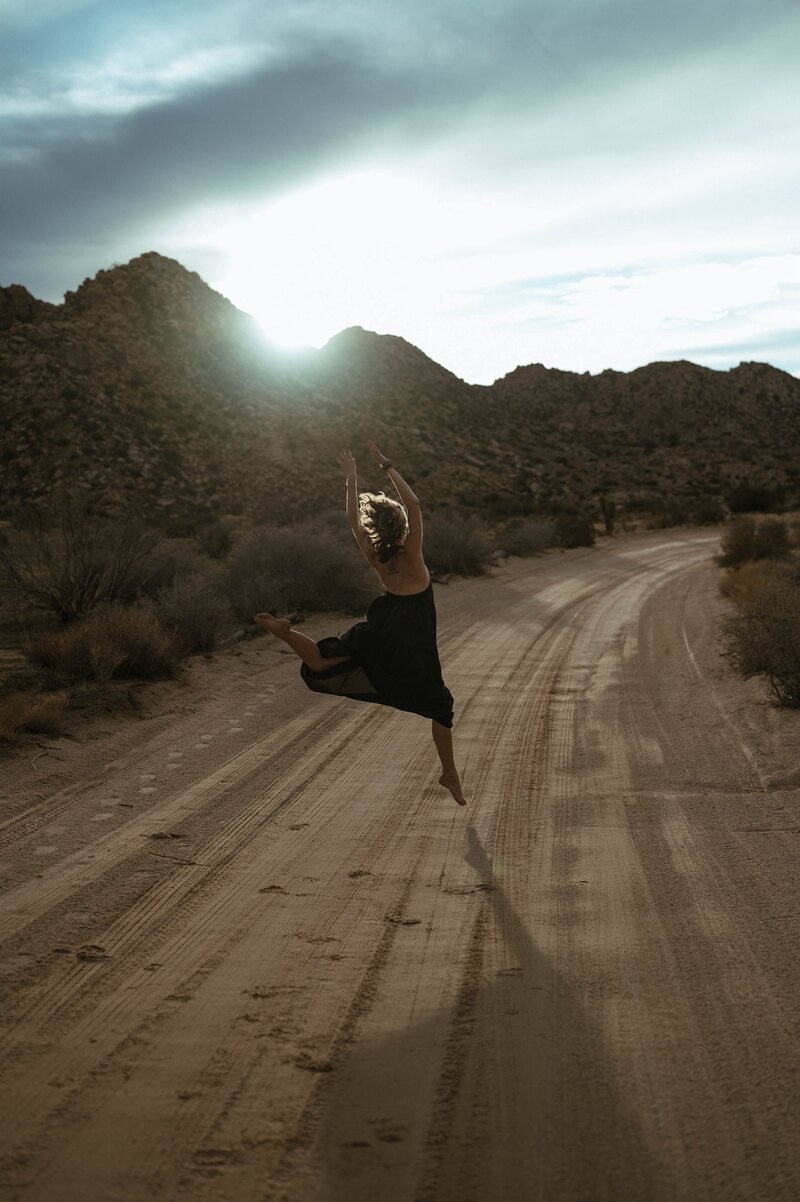 Woman joyfully jumping on a dirt road