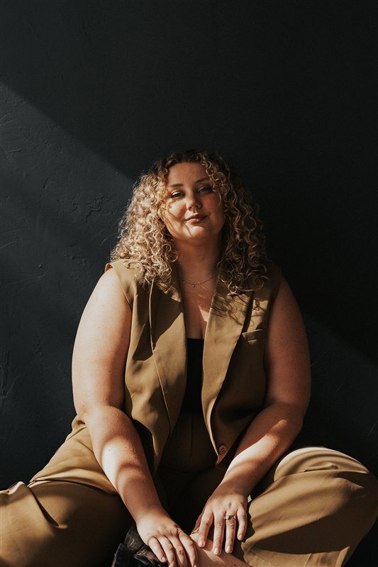 Andrea Cakmar sits on the floor in a confident pose.