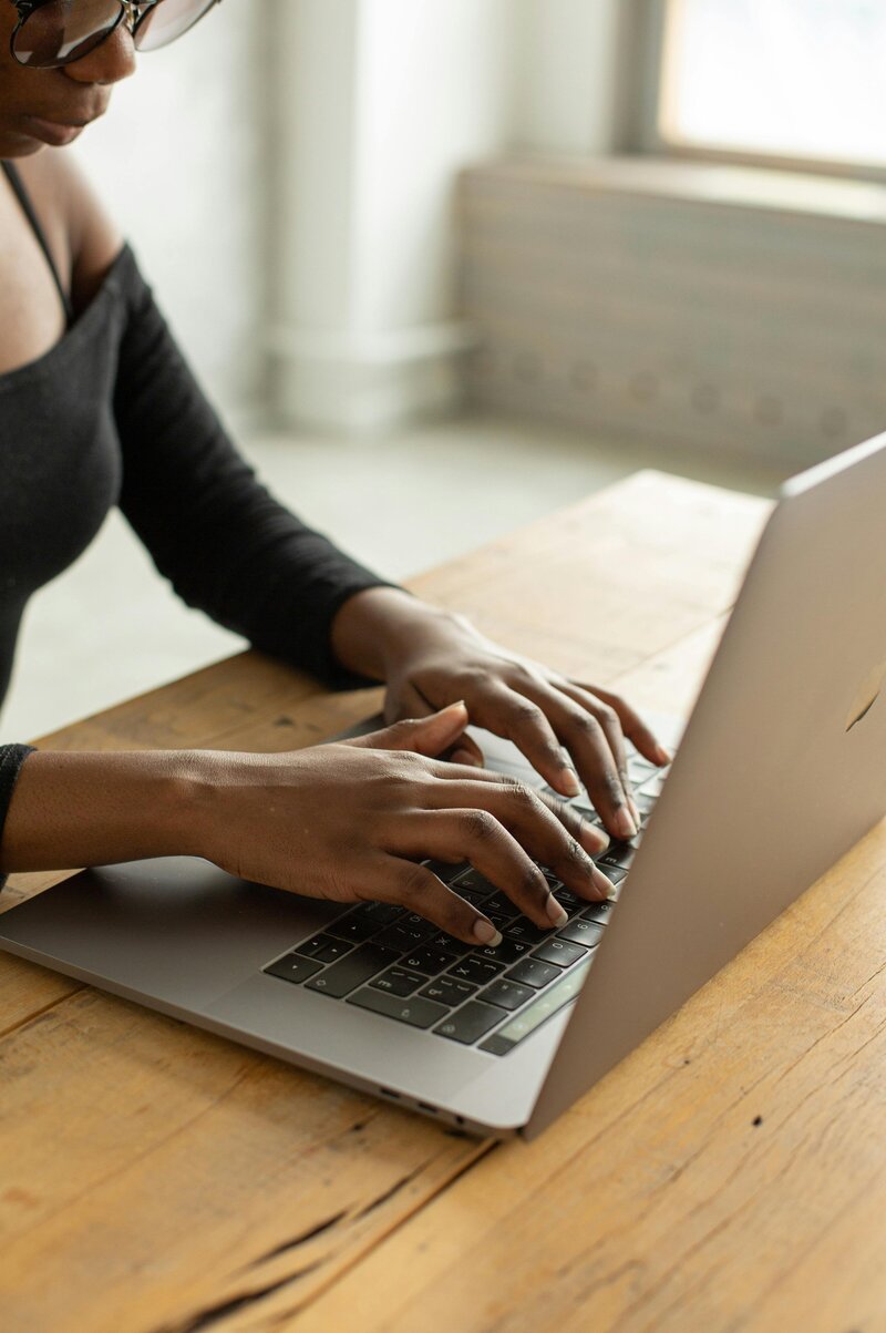 Woman writing in a notebook with a computer
