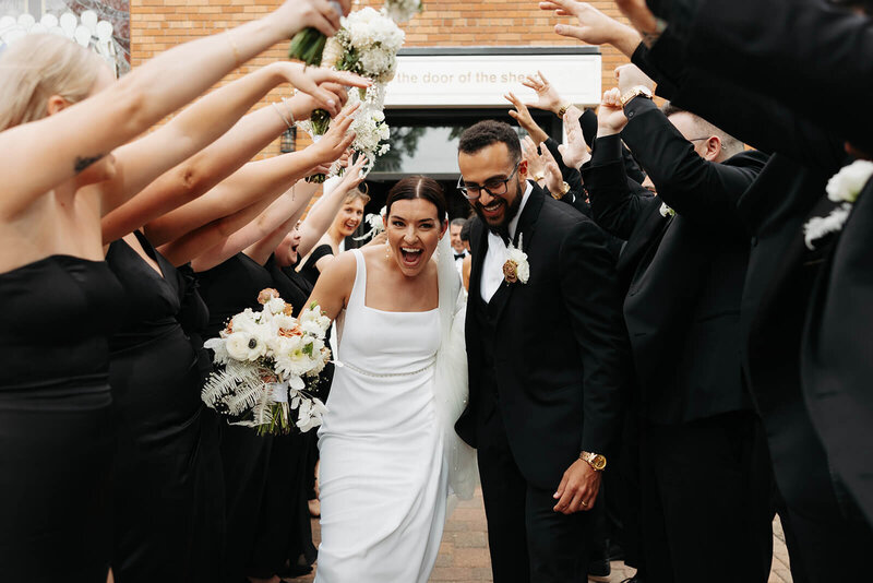Bride and groom walk through tunnel of friends and family after tying the knot