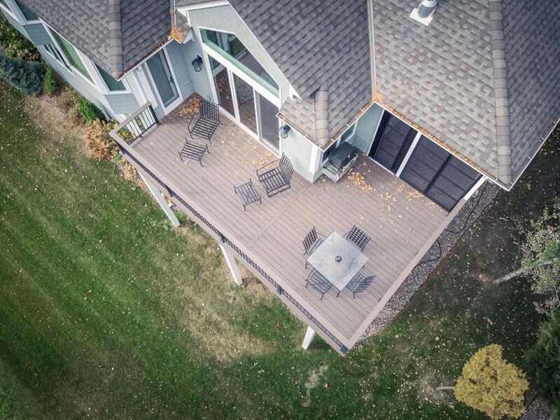 Aerial top view of a composite deck and attached screened-in porch with patio furniture. 