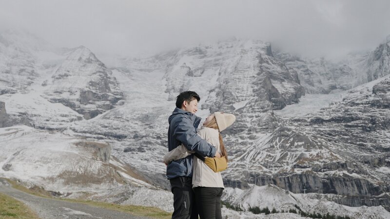 Los Angeles wedding videographer, Jimmy Shin Films,Jimmy and his wife, Min, hugging each other  in front of huge mountains in Switzerland.