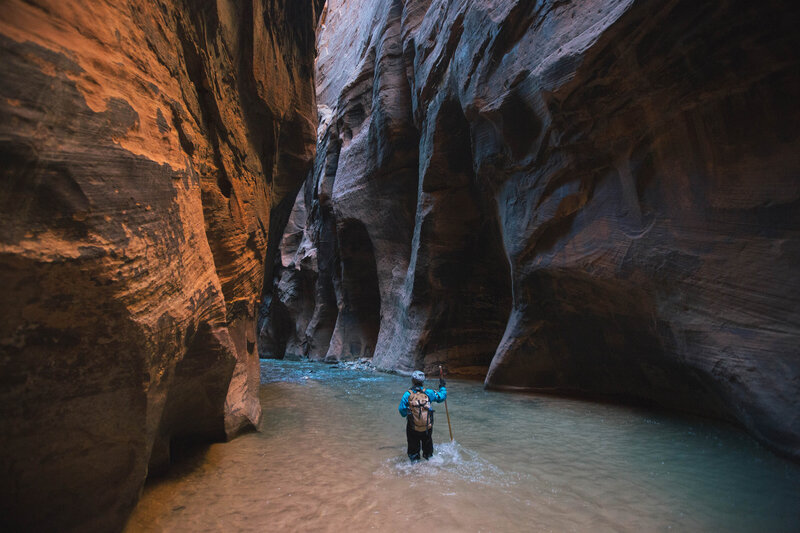 woman walks through a gorge in a canyon in water