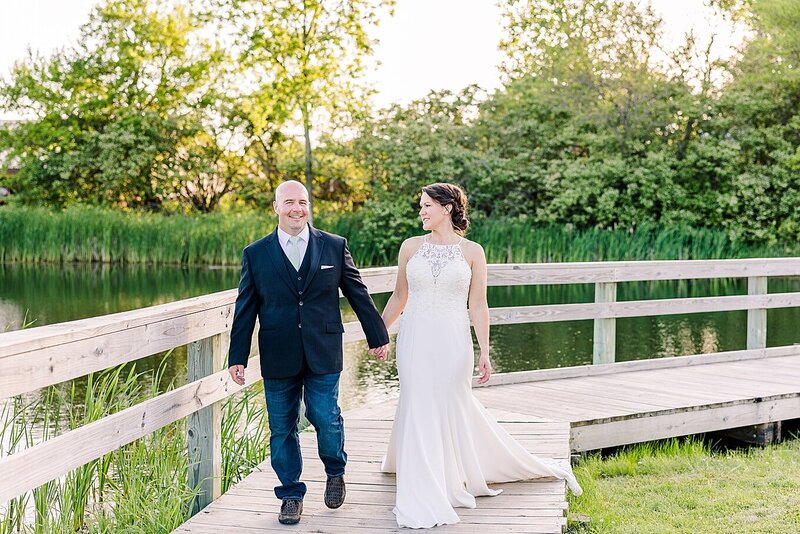 bride and groom holding hands in field