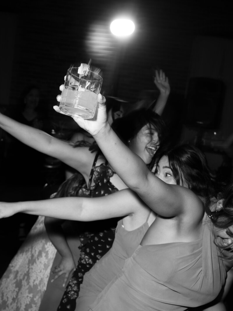 A black and white photo of guests dancing at a lively wedding reception in Downtown Denver, Colorado.