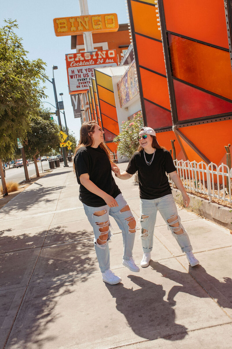 Two girls laughing in front of a red wall building